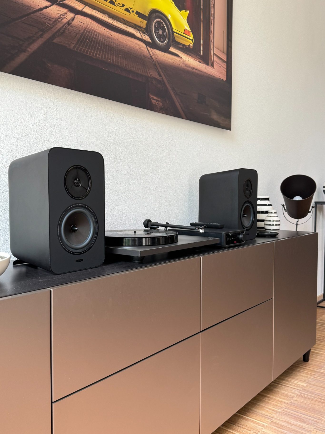 Rega System One Schwarze Lautsprecher und Plattenspieler auf einem modernen Möbelstück.