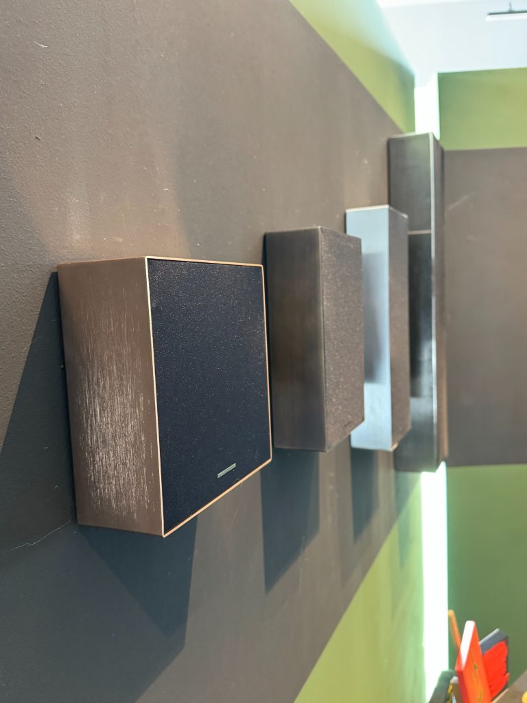 Wandlautsprecher Vier Lautsprecher in unterschiedlichen Größen an einer Wand montiert.