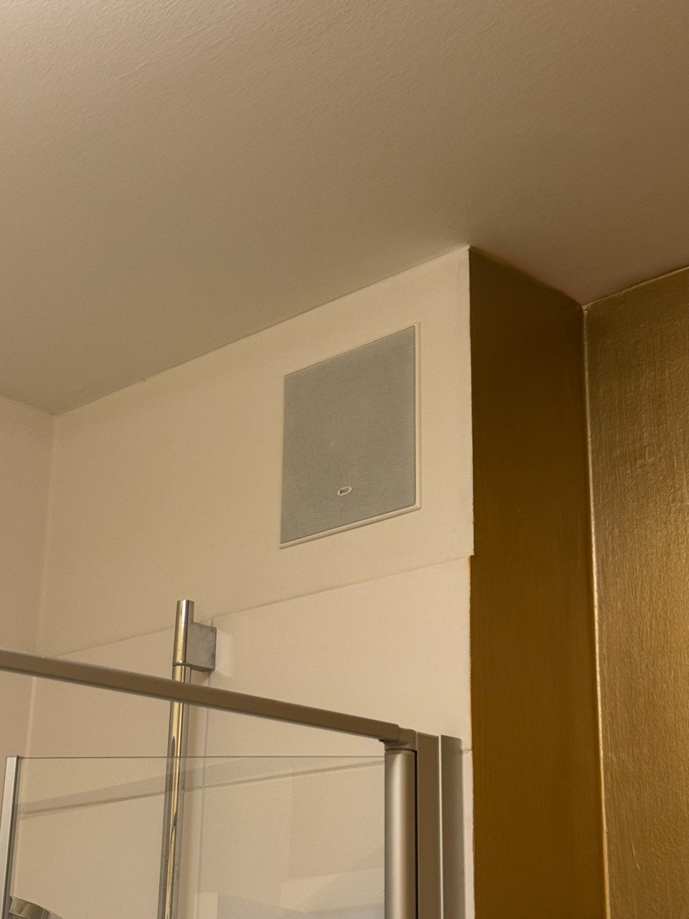 KEF In-Wall Wandlautsprecher in einer Ecke, über einer Duschabtrennung.