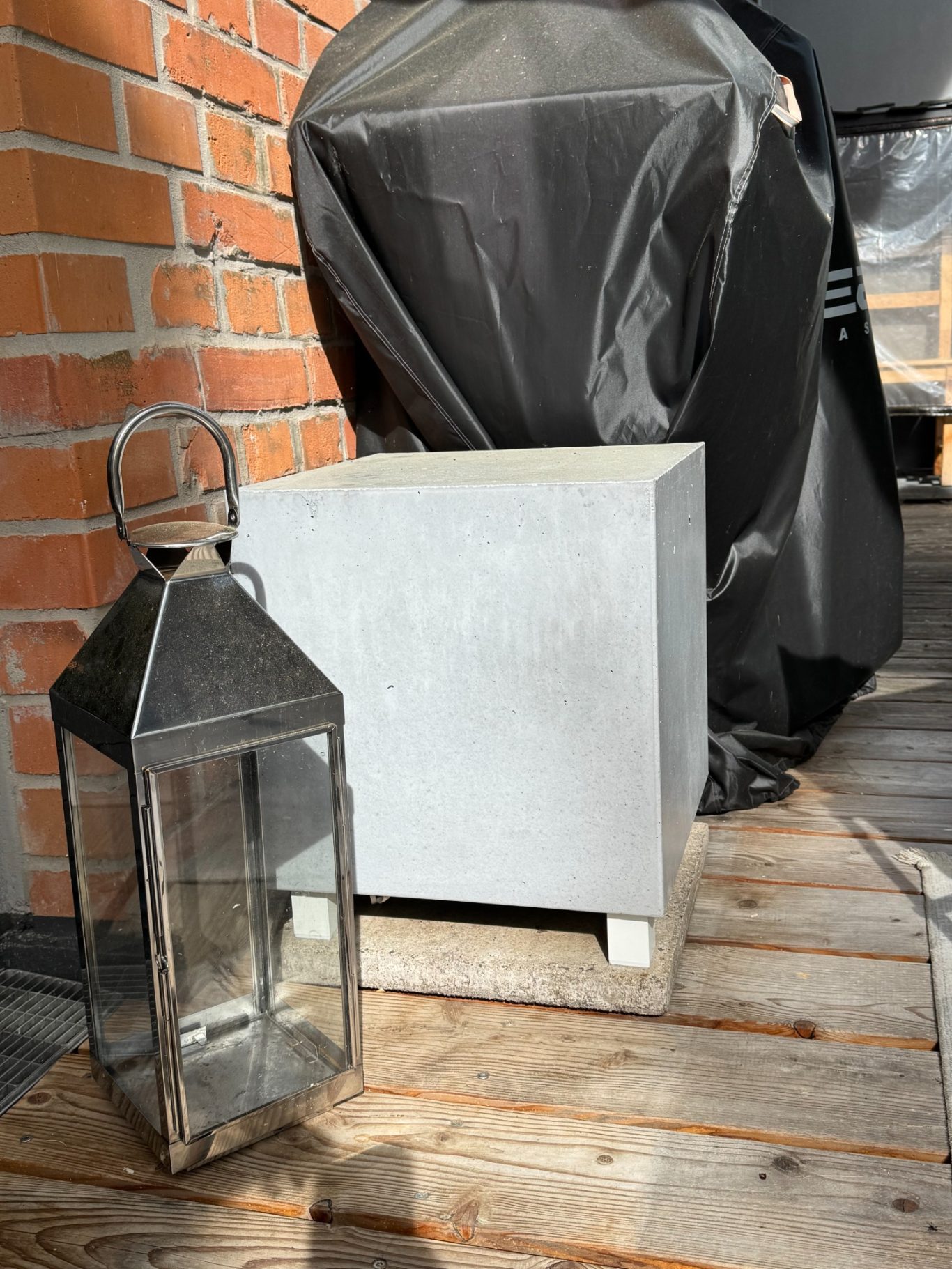 4moor Beton-Subwoofer Eisenlaterne neben einem grauen Betonsubwoofer auf einem Holzboden.
